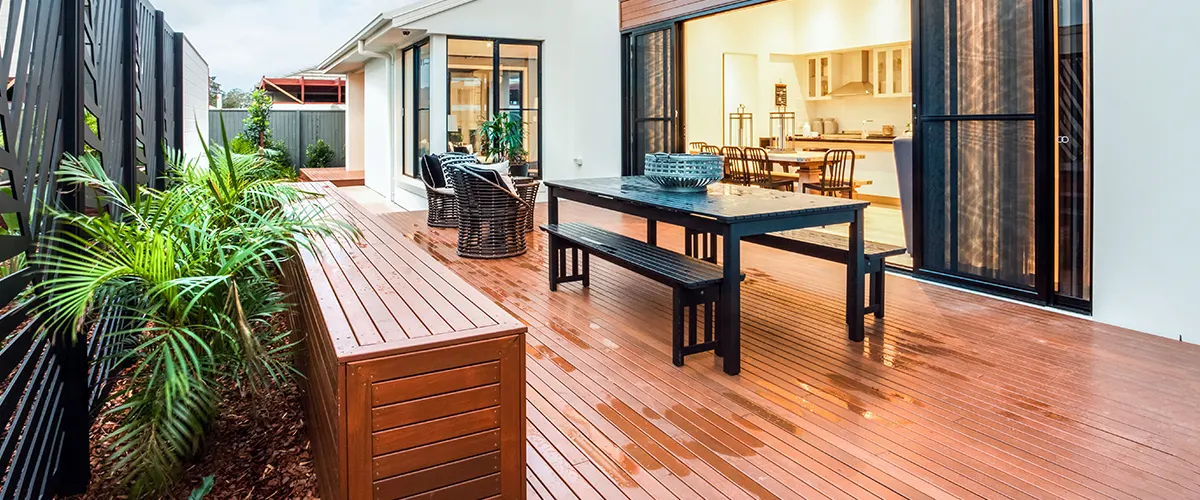 A beautiful deck made of wood with a table and a glass door