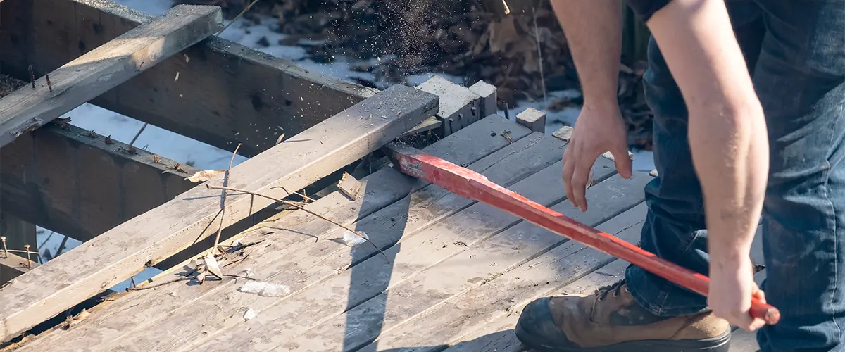 A man destroying an old deck frame