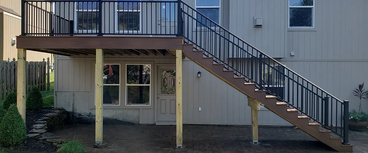 An elevated deck on the side of the house with stairs and aluminum railings