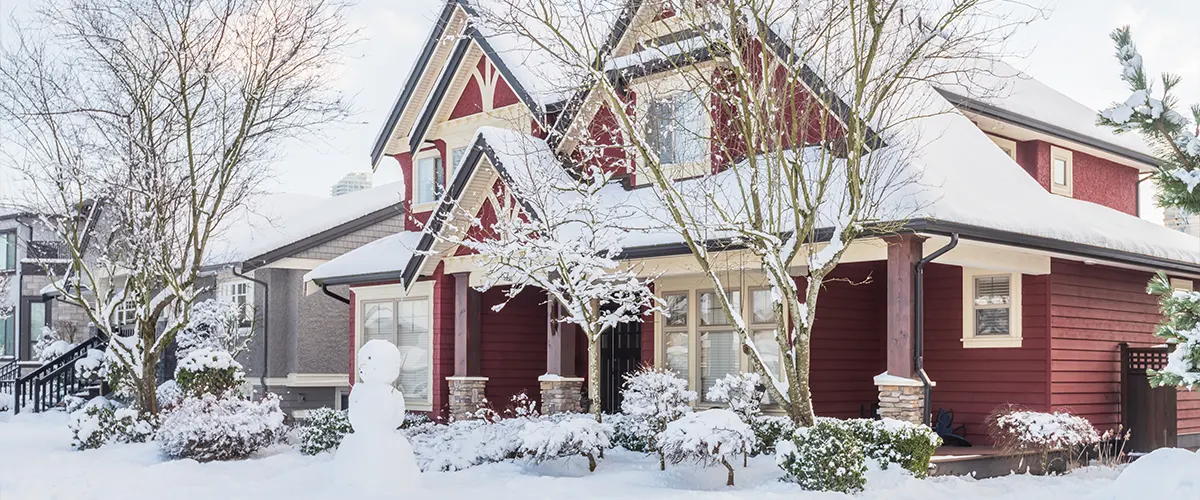 A house with red siding covered in snow
