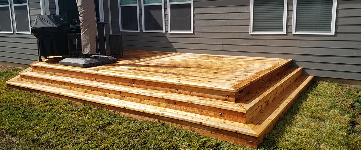 A deck on the same level with the ground with a big closed umbrella and stairs