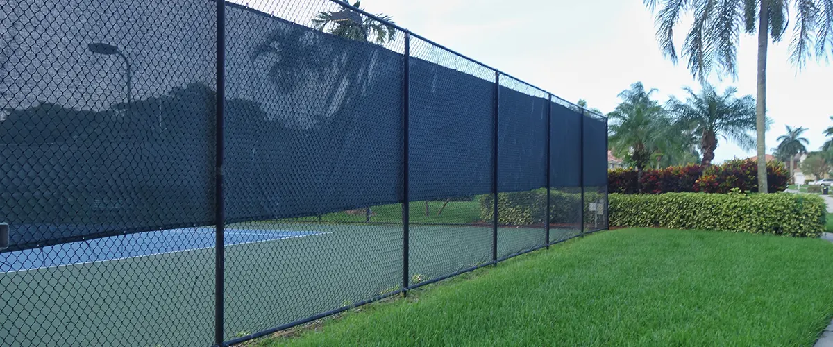 A chain link fence with a textile mesh that delimitates a tennis field