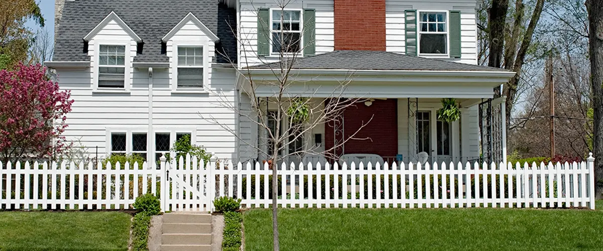 A big home with a small vinyl picket fence