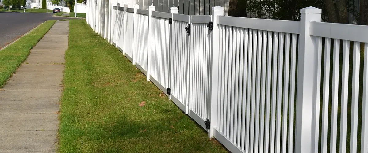 White vinyl fence with black hinges on gate