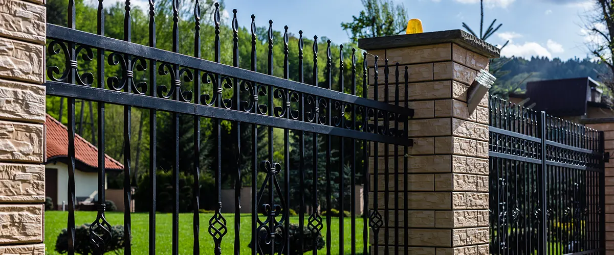 A metal gate with masonry pillars that create a fancy design