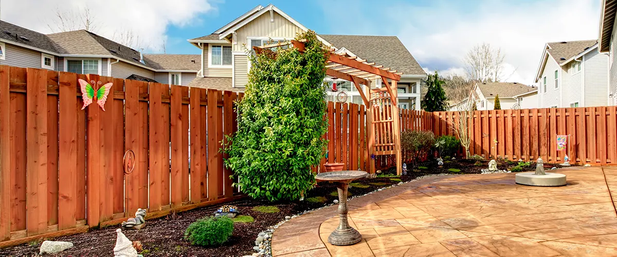 A redwood fence with a big tree near it and a driveway