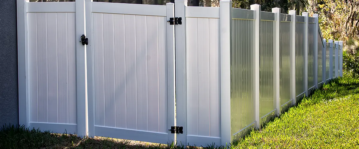 A white fence made of vinyl panels with a small gate