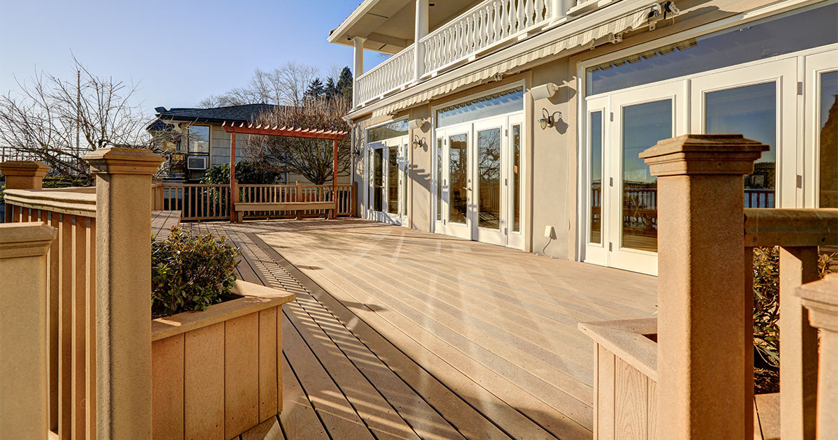 A composite decking with composite railings attached to a house with many glass doors
