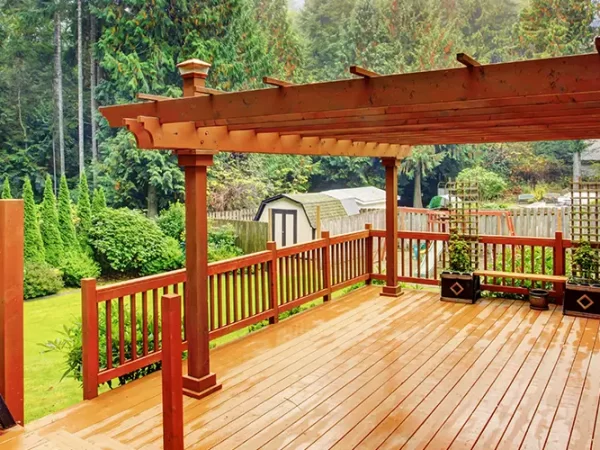 Wooden deck with pergola and bench in backyard